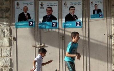 Children play past campaign posters displaying an electoral list ahead of municipal elections in the northern West Bank city of Nablus, on May 10, 2017 (AFP/Jaafar Ashtiyeh)