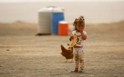 Illustrative image of a displaced child, who fled from the Islamic State (IS) group bastion of Raqqa, standing outside as she eats a loaf of bread in a camp for displaced near the town of al-Karamah on May 10, 2017. (AFP PHOTO / DELIL SOULEIMAN)