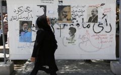 An Iranian woman walks past campaign posters on a commercial street in southern Tehran's Molavi neighborhood on May 11, 2017.
(Atta Kenare/AFP)