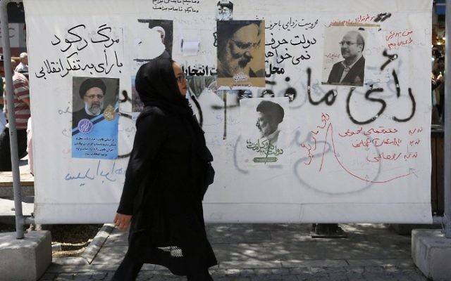 An Iranian woman walks past campaign posters on a commercial street in southern Tehran's Molavi neighborhood on May 11, 2017.
(Atta Kenare/AFP) An Iranian woman walks past campaign posters on a commercial street in southern Tehran's Molavi neighborhood on May 11, 2017.
(Atta Kenare/AFP)