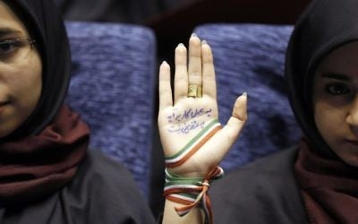 A supporter of Iranian conservative presidential candidate and Tehran mayor Mohammad Bagher Ghalibaf attends a campaign rally in the Iranian capital Tehran on May 14, 2017, with her hand wrapped with a band carrying the colors of the Iranian national flag and ink on her palm reading in Persian: "With action not by speech you can finish the job and work."  (AFP PHOTO / ATTA KENARE)