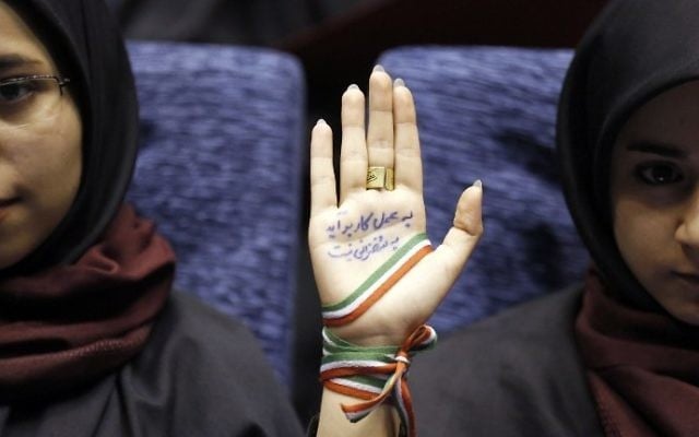 A supporter of Iranian conservative presidential candidate and Tehran mayor Mohammad Bagher Ghalibaf attends a campaign rally in the Iranian capital Tehran on May 14, 2017, with her hand wrapped with a band carrying the colors of the Iranian national flag and ink on her palm reading in Persian: "With action not by speech you can finish the job and work." (AFP PHOTO / ATTA KENARE) A supporter of Iranian conservative presidential candidate and Tehran mayor Mohammad Bagher Ghalibaf attends a campaign rally in the Iranian capital Tehran on May 14, 2017, with her hand wrapped with a band carrying the colors of the Iranian national flag and ink on her palm reading in Persian: "With action not by speech you can finish the job and work." (AFP PHOTO / ATTA KENARE)