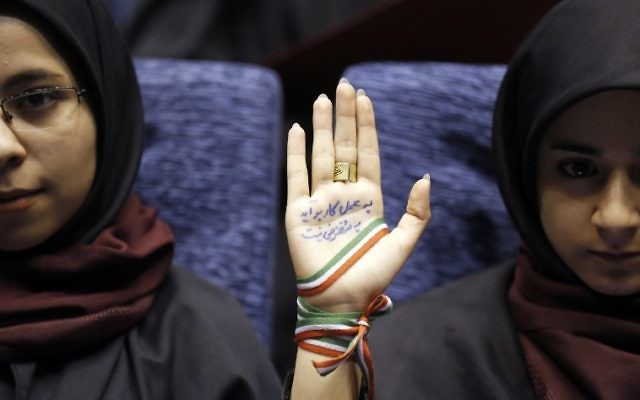 A supporter of Iranian conservative presidential candidate and Tehran mayor Mohammad Bagher Ghalibaf attends a campaign rally in the Iranian capital Tehran on May 14, 2017, with her hand wrapped with a band carrying the colours of the Iranian national flag and ink on her palm reading in Persian: "With action not by speech you can finish the job and work." (AFP PHOTO / ATTA KENARE)