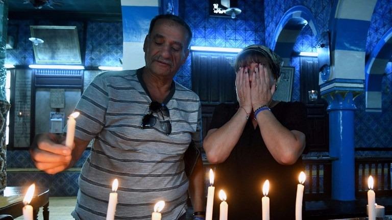 A Tunisian Jewish family lights candles at the Ghriba Synagogue on the Tunisian resort island of Djerba on May 14, 2017 during the second day of the annual Jewish pilgrimage to the synagogue thought to be Africa's oldest. (FETHI BELAID / AFP) A Tunisian Jewish family lights candles at the Ghriba Synagogue on the Tunisian resort island of Djerba on May 14, 2017 during the second day of the annual Jewish pilgrimage to the synagogue thought to be Africa's oldest. (FETHI BELAID / AFP)