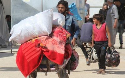 Syrians carry their belongings as civilians and rebels, who were evacuated from the Qabun district in northeast Damascus, arrive at a temporary camp in the northern countryside of Idlib province on May 15, 2017. (Omar Haj Kadour/AFP)