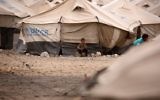 A displaced Syrian child, who fled the countryside surrounding the Islamic State group stronghold of Raqqa, sitting outside a tent at a temporary camp in the village of Ain Issa, Syria, May 1, 2017. (AFP/DELIL SOULEIMAN)