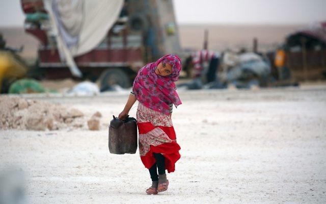 A displaced Syrian child, who fled the countryside surrounding the Islamic State group stronghold of Raqqa, carrying a jerrycan as she walks at a temporary camp in the village of Ain Issa, Syria, May 1, 2017. (AFP/DELIL SOULEIMAN)