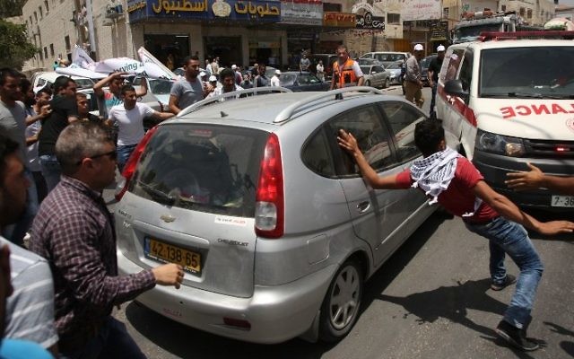 Palestinian protesters attack a car reportedly driven by an Israeli settler as it attempts to cross a crowd of demonstrators near the Hawara military checkpoint in the northern West Bank on May 18, 2017. (AFP Photo/Jaafar Ashtiyeh) Palestinian protesters attack a car reportedly driven by an Israeli settler as it attempts to cross a crowd of demonstrators near the Hawara military checkpoint in the northern West Bank on May 18, 2017. (AFP Photo/Jaafar Ashtiyeh)