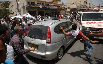 Palestinian protesters surround a car reportedly driven by an Israeli settler as it attempts to cross a crowd of demonstrators near the Hawara military checkpoint in the northern occupied West Bank on May 18, 2017. (AFP PHOTO / JAAFAR ASHTIYEH)