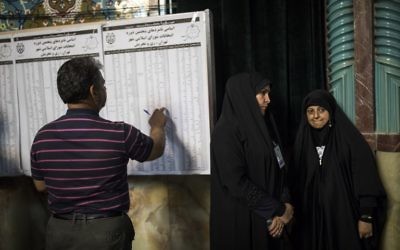 An Iranian man checks the list of municipal council elections ahead of voting at a polling station in Tehran on May 19, 2017. / AFP PHOTO / Behrouz MEHRI