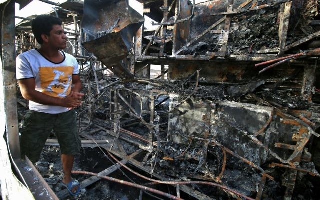An Iraqi man inspects the wreckage of a bus, that was damaged following a car bomb attack, in the southern Iraqi city of Basra on May 20, 2017. (AFP PHOTO / HAIDAR MOHAMMED ALI)