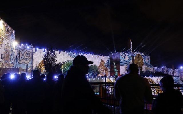 People watch an audio slideshow projected on the ancient walls of Jerusalem's Old City on May 20, 2017, on the beginning of the week marking the 50th anniversary of the 1967 Six Day War. (AFP PHOTO / GALI TIBBON)