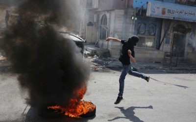 A Palestinian man throws stones at Israeli security forces during clashes in the West Bank city of Qalandiya, north of Jerusalem, on May 22, 2017. (Abbas Momani/AFP)
