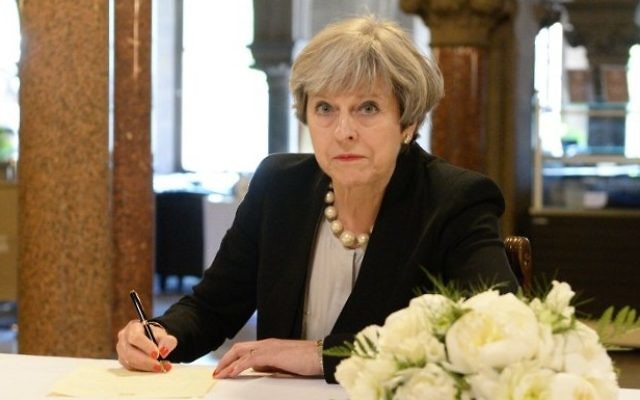 Britain's Prime Minister Theresa May writes a message in a book of condolence at Manchester Town Hall in Manchester, northwest England, on May 23, 2017, following the terror attack at the Ariana Grande concert at the Manchester Arena in Manchester on May 22. (AFP / POOL / Ben Birchall)