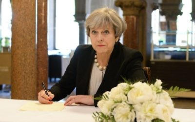 Britain's Prime Minister Theresa May writes a message in a book of condolence at Manchester Town Hall on May 23, 2017, following the terror attack at the Ariana Grande concert at the Manchester Arena on May 22. (Ben Birchall/Pool/AFP)