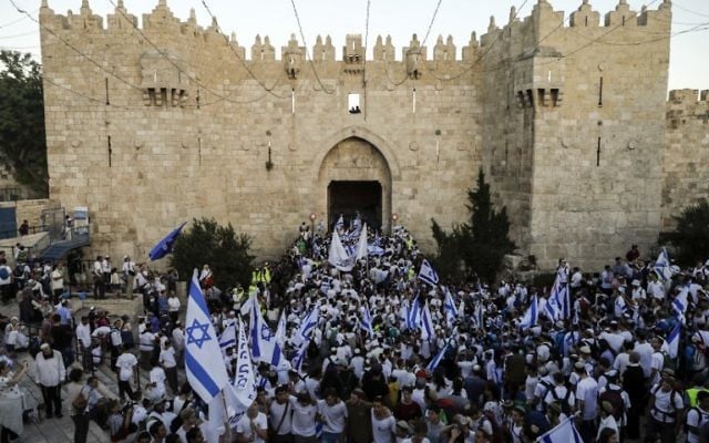 Israelis wave the Israeli flag as they parade through Damascus Gate in Jerusalem's Old City on May 24, 2017 to commemorate Jerusalem Day, marking the reunification of the city following the Six Day War of 1967. (AFP PHOTO / Menahem KAHANA)