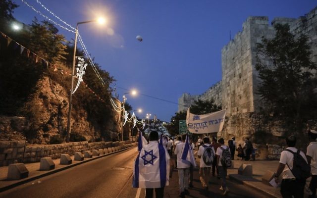 Israelis wearing Israeli flags parade around Jerusalem's Old City on May 24, 2017, to commemorate Jerusalem Day, marking the reunification of the city following the Six Day War of 1967. (AFP PHOTO / Menahem KAHANA)