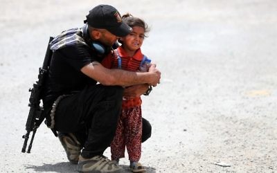 An Iraqi soldier helps a displaced girl after leaving their homes west of Mosul on May 26, 2017, as government forces continue their offensive to retake the city of Mosul from Islamic State (IS) group fighters. (AFP/Karim Sahib)