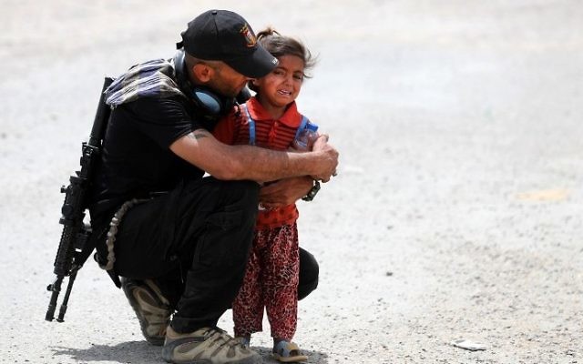 An Iraqi soldier helps a displaced girl after leaving their homes west of Mosul on May 26, 2017, as government forces continue their offensive to retake the city of Mosul from Islamic State (IS) group fighters. (AFP/Karim Sahib) An Iraqi soldier helps a displaced girl after leaving their homes west of Mosul on May 26, 2017, as government forces continue their offensive to retake the city of Mosul from Islamic State (IS) group fighters. (AFP/Karim Sahib)