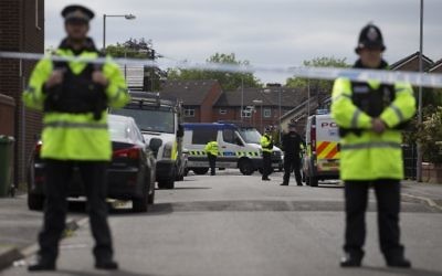 Police officers guard the entrance to a street in the Moss Side area of Manchester on May 28, 2017 during an operation. (AFP/ JOHN SUPER)