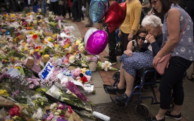 Days after a suicide bombing at an Ariana Grande concert that left more than 20 people dead and many more injured, women cry after placing flowers in a square at a vigil for the victims of the in central Manchester, England, May 24, 2017. (AP/Emilio Morenatti) 