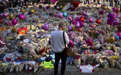 A man stands next to flowers for the victims of Monday's bombing at St Ann's Square in central Manchester, England, Friday, May 26 2017. (AP Photo/Emilio Morenatti)