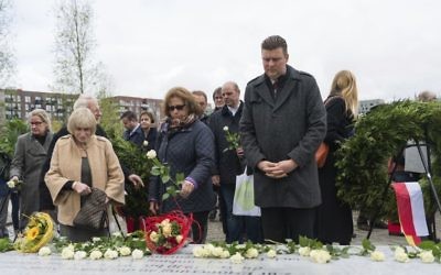 People place white roses on a memorial that was unveiled in the German port city of Hamburg to Jewish and Roma residents who were killed during the Nazi Holocaust, Wednesday, May 10, 2017. (Christophe Gateau/dpa via AP)