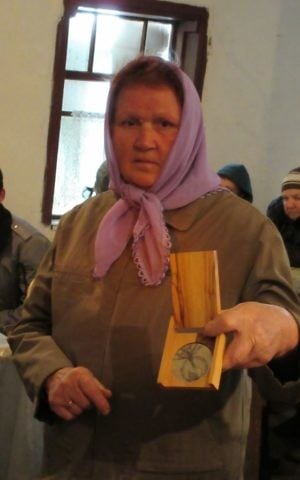 Alexandra Melnik, whose father and grandfather saved a Jewish family during World War ll, shows a Righteous Among the Gentiles medal from Yad Vashem at the synagogue of Bershad, central Ukraine, May 11, 2017. (Sue Surkes)