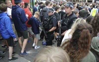 Armed police watch as fans arrive for a concert at Old Trafford cricket ground in Manchester, England Saturday May 27 2017. (AP Photo/Rui Vieira)