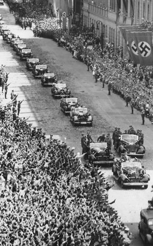 German Chancellor Adolf Hitler stands in the front car of a motorcade upon his arrival at the chancellery in Berlin on July 6, 1940, after returning from Compiegne, where France surrendered to Germany. (AP Photo/Franz Roth)