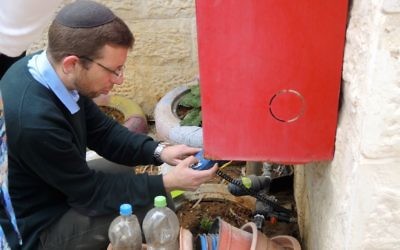 Avishai Himelfarb, the founder and director of Leshomra, checks a watering system at a school garden in Modiin Ilit on March 22, 2017. (Melanie Lidman/Times of Israel)