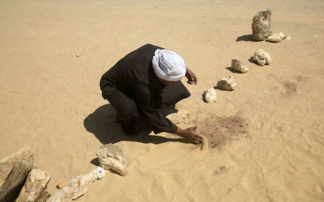 A man covers the blood stains of victims on the road leads to St. Samuel, the Confessor monastery in Maghagha, about 220 kilometers (140 miles) south of Cairo, Egypt, Saturday, May 27, 2017. (AP Photo/Amr Nabil)