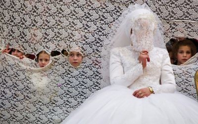 Illustrative: Young girls peek through a curtain next to the bride at an ultra-Orthodox wedding on January 18, 2016. (Yaakov Lederman/Flash90)