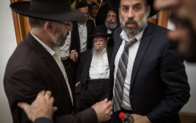 Former Sephardic chief rabbi Eliyahu Bakshi-Doron, sitting center, arrives at the Jerusalem District Court surrounded by supporters who try to hide his face,  May 15, 2017. (Hadas Parush/Flash90)