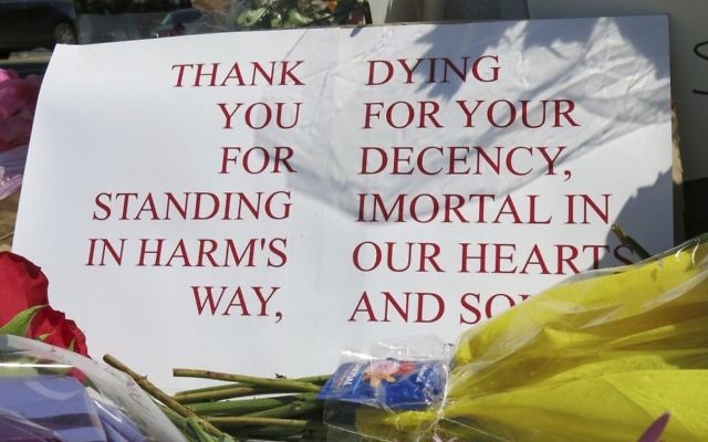 A sign of thanks rests against a traffic light pole at a memorial outside the transit center in Portland, Ore. on Saturday, May 27, 2017. (AP Photo/Gillian Flaccus)