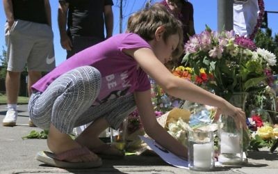 Coco Douglas, 8, leaves a handmade sign and rocks she painted at a memorial in Portland, Ore., on Saturday, May 27, 2017, for two bystanders who were stabbed to death Friday while trying to stop a man who was yelling anti-Muslim slurs and acting aggressively toward two young women. (AP/Gillian Flaccus)