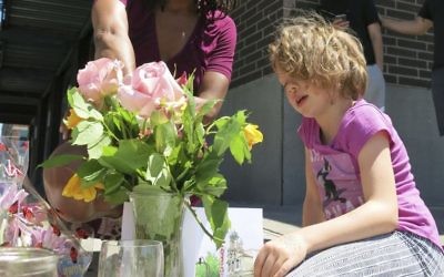 Angel Sauls, not seen, helps her stepdaughter, Coco Douglas arrange a sign and some painted rocks she made for a memorial in Portland, Ore., on Saturday, May 27, 2017, for two bystanders who were stabbed to death Friday while trying to stop a man who was yelling anti-Muslim slurs and acting aggressively toward two young women. (AP/Gillian Flaccus)