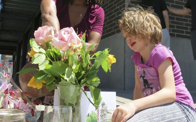 Angel Sauls, not seen, helps her stepdaughter, Coco Douglas arrange a sign and some painted rocks she made for a memorial in Portland, Ore., on Saturday, May 27, 2017, for two bystanders who were stabbed to death Friday while trying to stop a man who was yelling anti-Muslim slurs and acting aggressively toward two young women. (AP/Gillian Flaccus) Angel Sauls, not seen, helps her stepdaughter, Coco Douglas arrange a sign and some painted rocks she made for a memorial in Portland, Ore., on Saturday, May 27, 2017, for two bystanders who were stabbed to death Friday while trying to stop a man who was yelling anti-Muslim slurs and acting aggressively toward two young women. (AP/Gillian Flaccus)