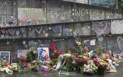 Flowers, candles and chalk tributes are seen on Tuesday, May 30, 2017, covering a memorial to two men who were fatally stabbed after shielding two young women from an anti-Muslim tirade on a Portland, Ore., light-rail train. (AP /Gillian Flaccus)
