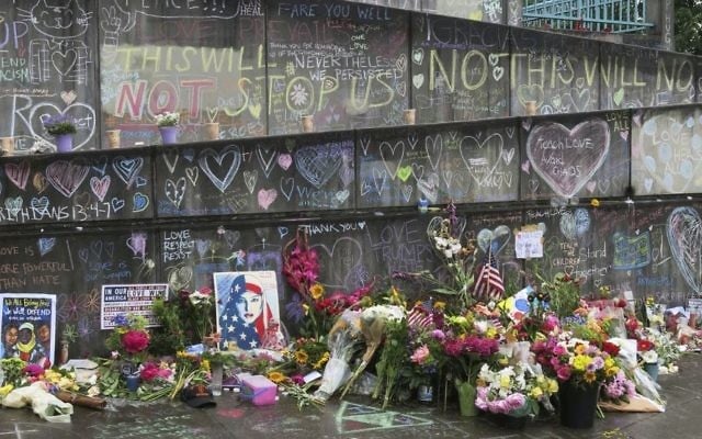 Flowers, candles and chalk tributes are seen on Tuesday, May 30, 2017, covering a memorial to two men who were fatally stabbed after shielding two young women from an anti-Muslim tirade on a Portland, Ore., light-rail train. (AP /Gillian Flaccus)