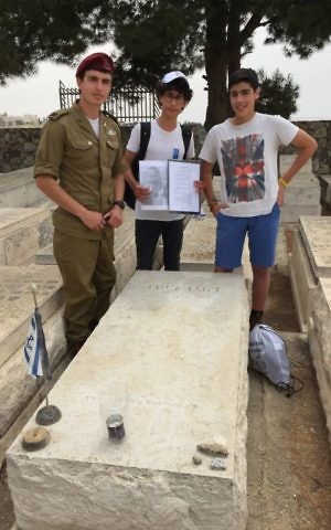 Students Moshe Abulafia (middle) and Yotam Marsh with a soldier at the grave of Heinz Beit, a German Jewish youth immigration official who is buried on the Mount of Olives (Jessica Steinberg/Times of Israel)