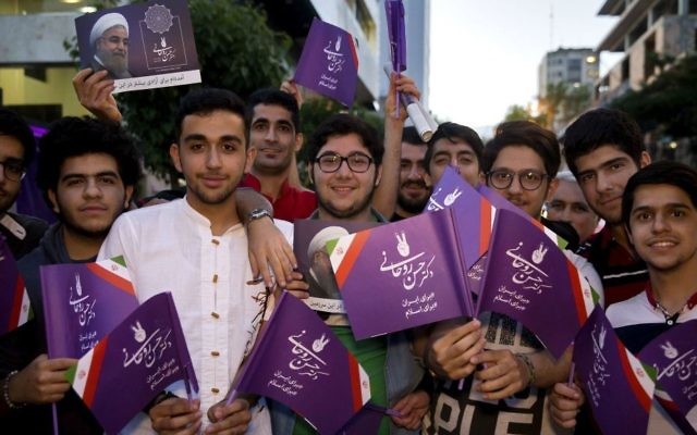 In this Wednesday May 10, 2017 photo, supporters of Iranian President Hassan Rouhani hold his posters for May 19 presidential election in downtown Tehran, Iran. (AP Photo/Ebrahim Noroozi) 