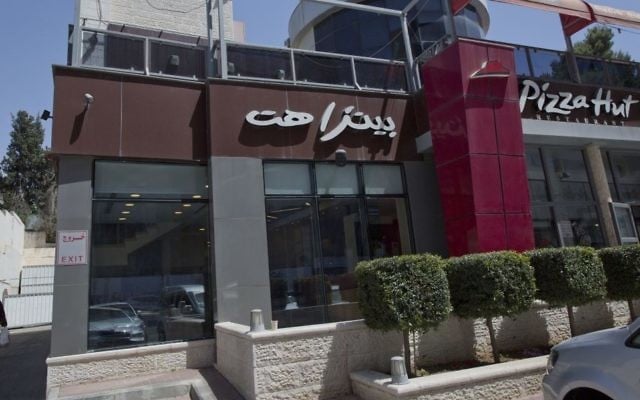 A woman walks by a Palestinian branch of the Pizza Hut company, in the West Bank city of Ramallah, Wednesday, May 10, 2017. (AP/Nasser Nasser) A woman walks by a Palestinian branch of the Pizza Hut company, in the West Bank city of Ramallah, Wednesday, May 10, 2017. (AP/Nasser Nasser)