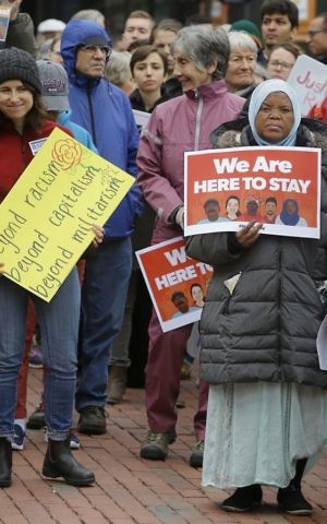 Sadia Mohamed, right, a naturalized citizen from Sudan, participates with protesters during a "Here to Stay" M1 Coalition May Day Immigration rally in front of the Statehouse Monday, May 1, 2017, in Boston. (AP/Stephan Savoia)