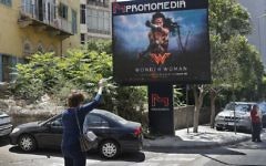 A woman waves for taxi, as she stands in front of a digital billboard promoting the 2017 Wonder Woman movie, in Beirut, Lebanon, Tuesday, May 30, 2017.  (AP Photo/Hussein Malla)