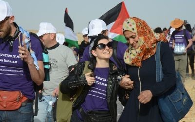 Activists hold hands as they make their way to the Sumud Freedom Camp in the South Hebron Hills on May 19, 2017. (Credit: Gili Getz)
