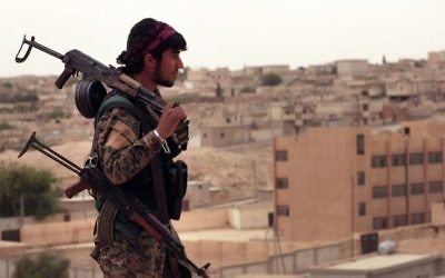 This April 30, 2017 photo shows a fighter from the SDF carrying weapons as he looks toward the northern town of Tabqa, Syria. (Syrian Democratic Forces, via AP)