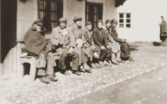 A group of concentration camp prisoners who were liberated on a death march from Dachau sit on a bench waiting to receive food from Japanese-American soldiers with the 522nd Field Artillery Battalion. (Courtesy USHMM/Eric Saul)