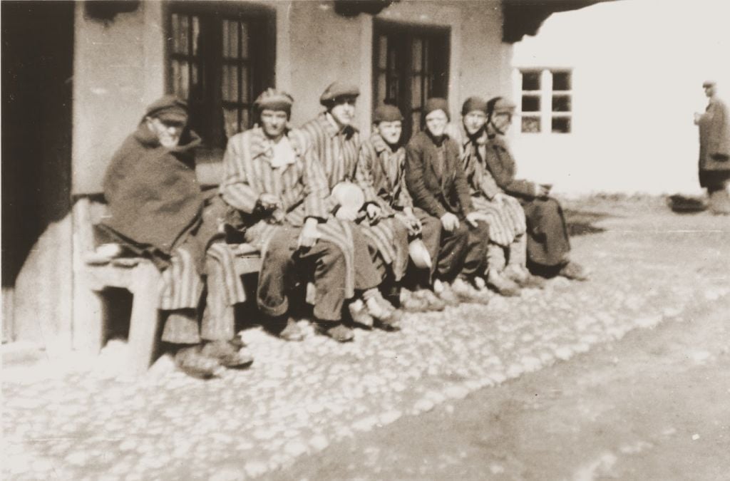 A group of concentration camp prisoners who were liberated on a death march from Dachau sit on a bench waiting to receive food from Japanese-American soldiers with the 522nd Field Artillery Battalion. (Courtesy USHMM/Eric Saul) A group of concentration camp prisoners who were liberated on a death march from Dachau sit on a bench waiting to receive food from Japanese-American soldiers with the 522nd Field Artillery Battalion. (Courtesy USHMM/Eric Saul)
