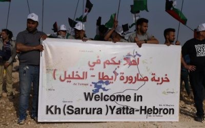 Activists hold the sign that was placed at the entrance of the Sumud Freedom Camp in the South Hebron Hills. They claim the location to have been where a Palestinian village called Sarura was once located. (Credit: Rami Ben-Ari) Activists hold the sign that was placed at the entrance of the Sumud Freedom Camp in the South Hebron Hills. They claim the location to have been where a Palestinian village called Sarura was once located. (Credit: Rami Ben-Ari)